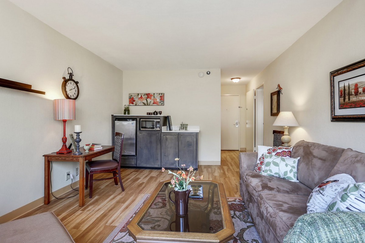 A cozy living room with a sofa, coffee table, and decorative elements on hardwood floors.