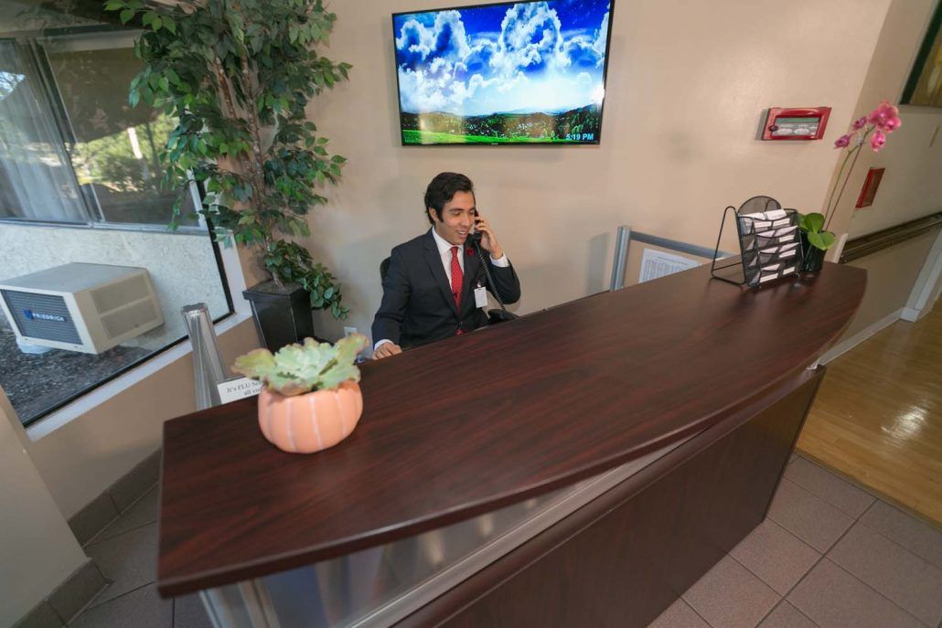 A person in a suit is making a phone call at a reception desk in an office setting.