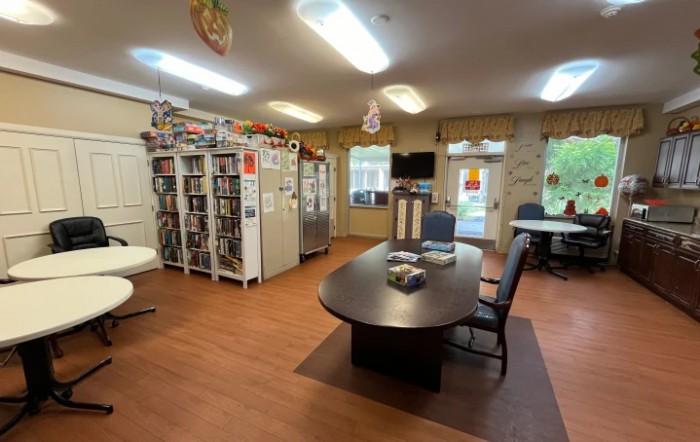 A modern office space featuring a large meeting table, bookshelves, and ample natural light.