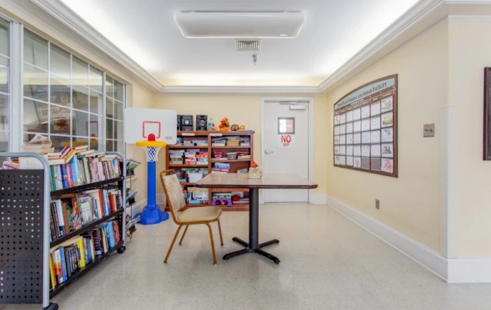A cozy library corner with bookshelves, table, and a small basketball hoop.