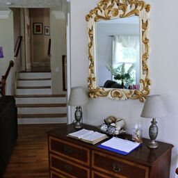 A cozy hallway featuring a decorative mirror, wooden desk, and lamps.