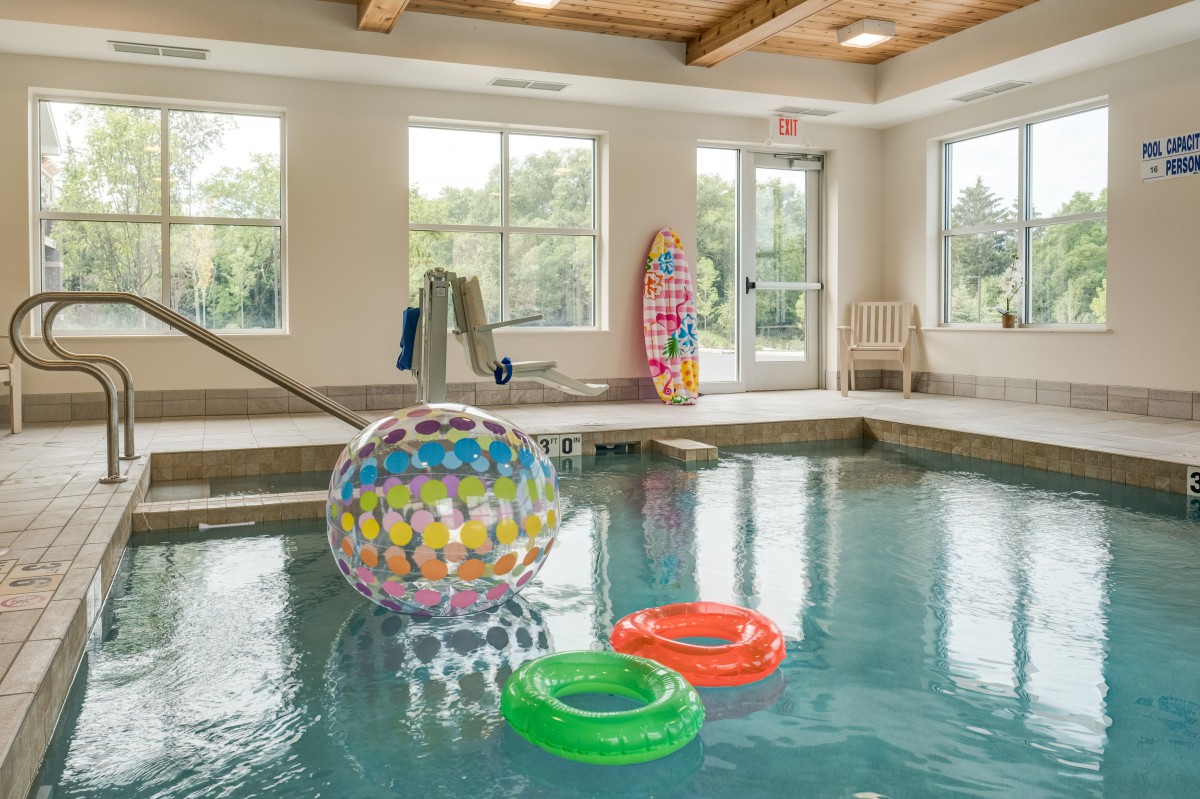 Indoor swimming pool with colorful inflatable toys and natural light from large windows.