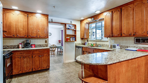 A well-designed modern kitchen featuring wooden cabinets and a granite countertop, seamlessly connected to a cozy dining area.