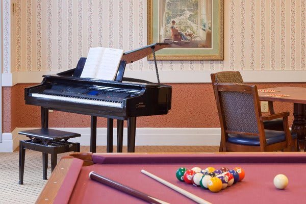 A cozy room featuring a piano with sheet music and a pool table with arranged billiard balls.