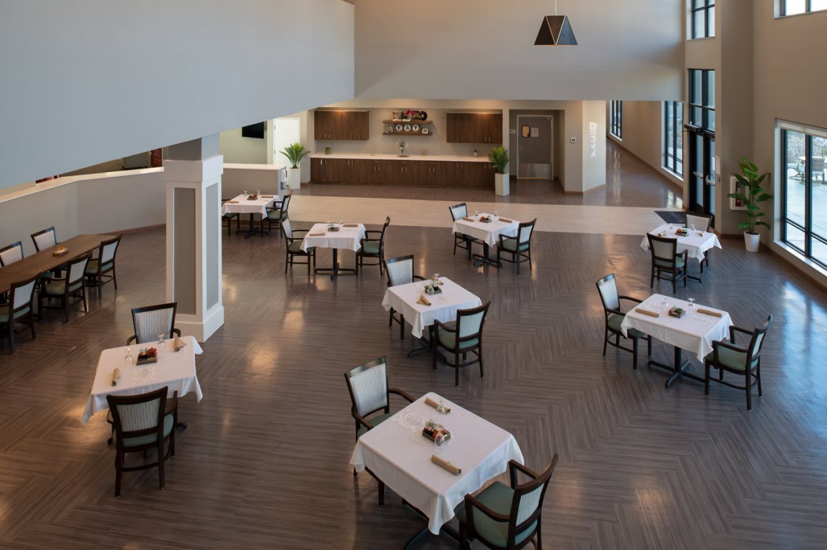 An empty restaurant dining area with neatly arranged tables and chairs, featuring a modern and spacious interior.