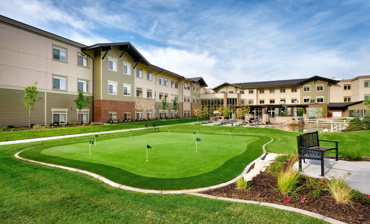 A scenic view of a residential building with a landscaped garden and a small golf putting green.