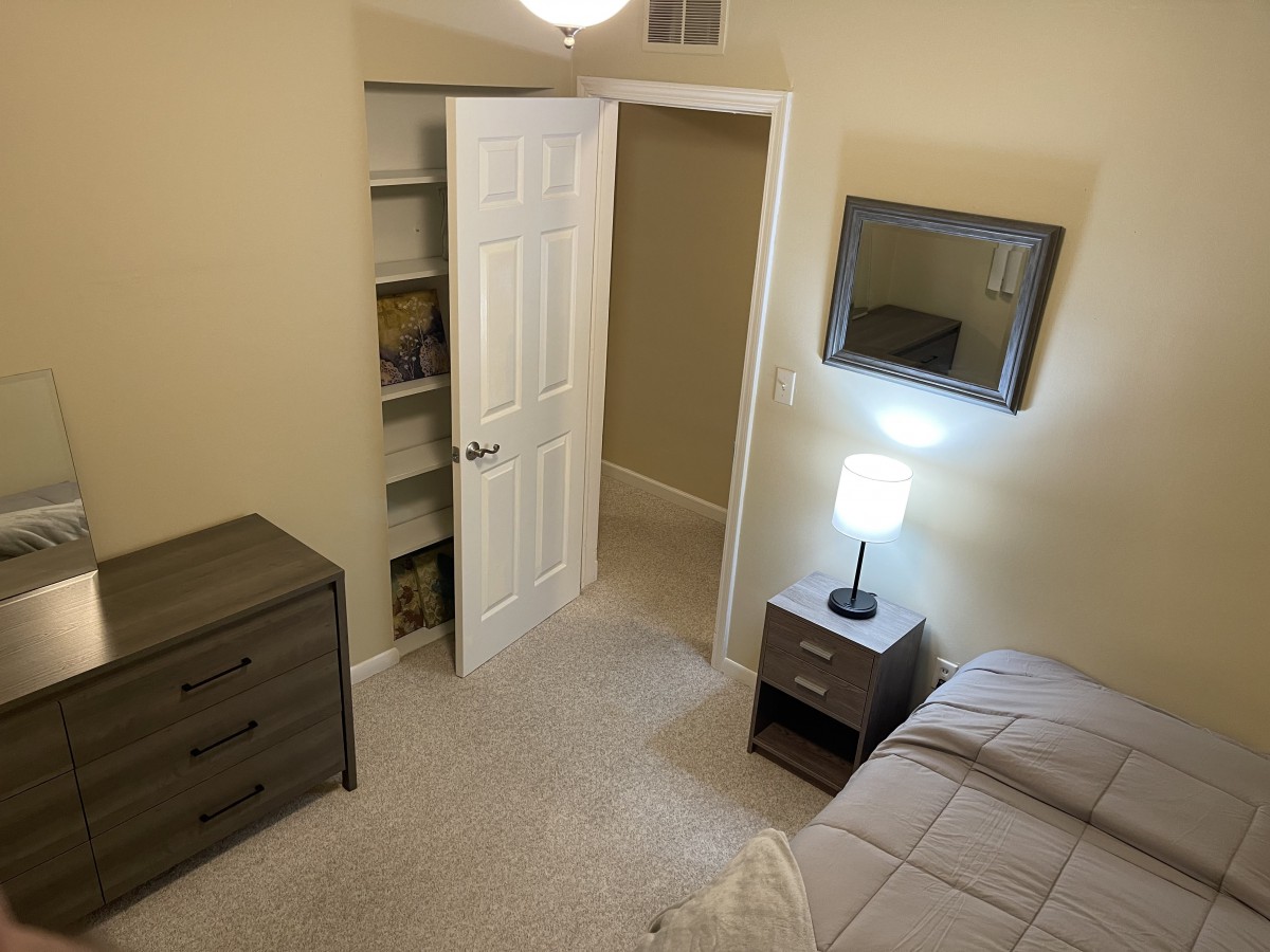 A cozy bedroom with a dresser, nightstand, and lamp.