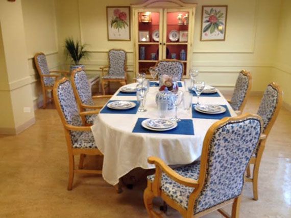 A well-set dining table in a formal dining room, complete with floral patterned chairs and elegant dinnerware.