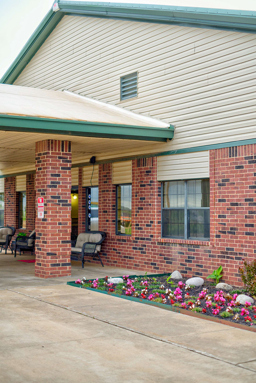 A hotel entrance with brick walls and a flowerbed.