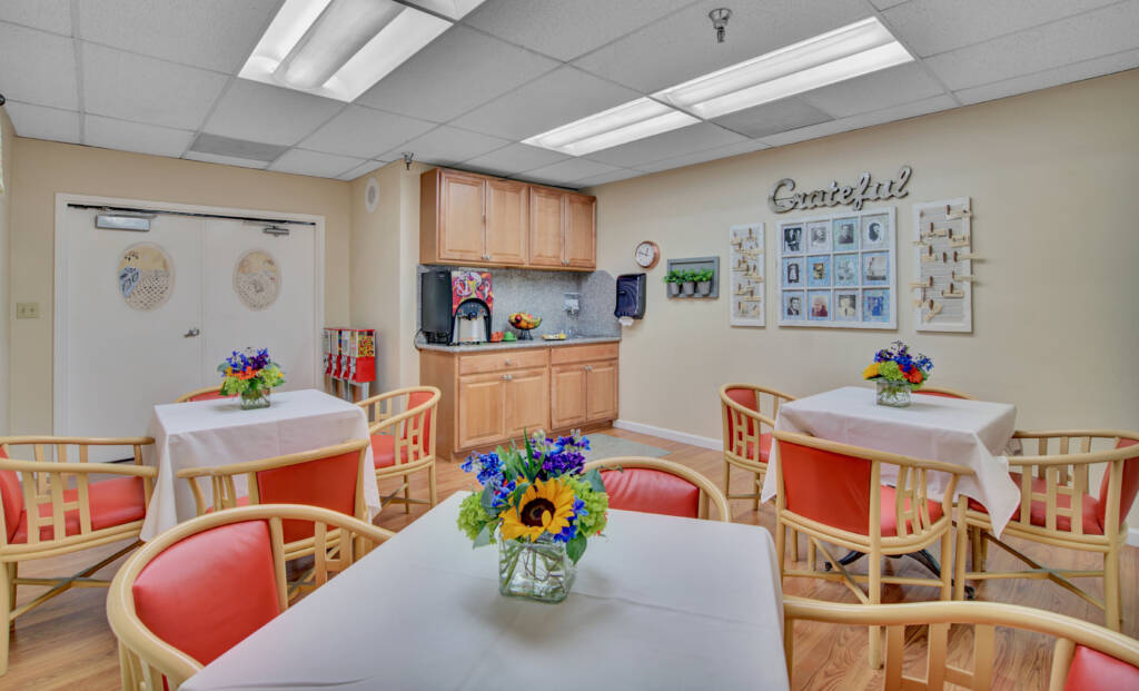 A cozy kitchen and dining area with neatly arranged tables and vibrant flower centerpieces.