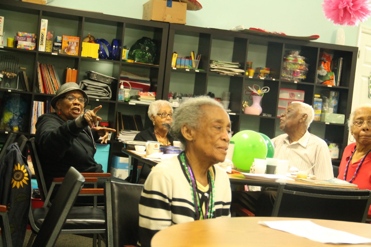A group of seniors enjoying a social gathering at a community center, surrounded by books and colorful decorations.