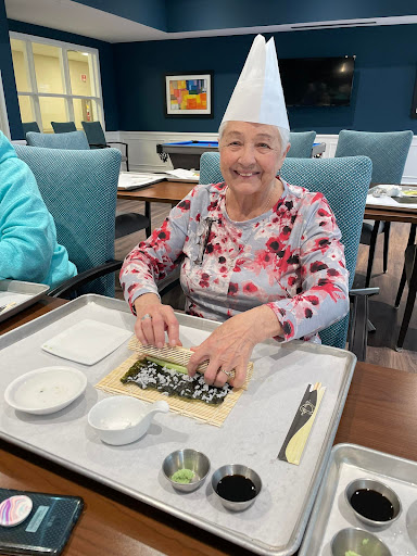 A joyful moment as a senior resident prepares sushi with care and enthusiasm.