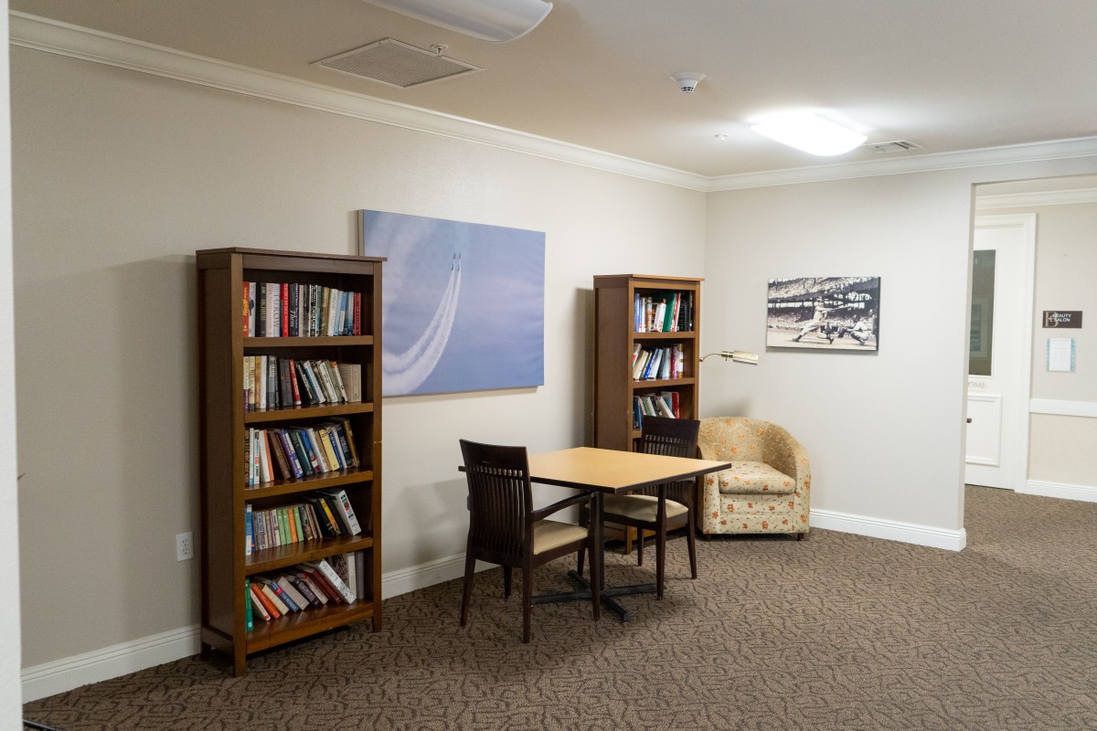 A cozy reading area with bookshelves, a small table with chairs, and comfortable seating.