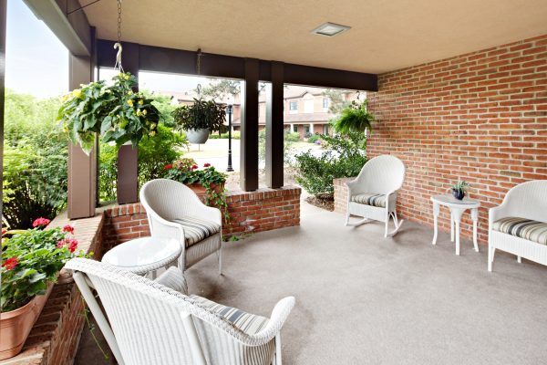 A cozy porch with wicker furniture and lush greenery.