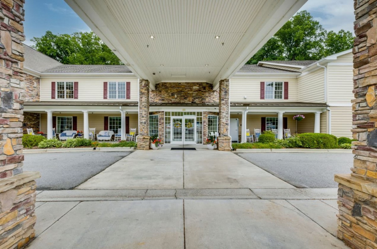 The main entrance of a residential building with columns and a landscaped driveway.