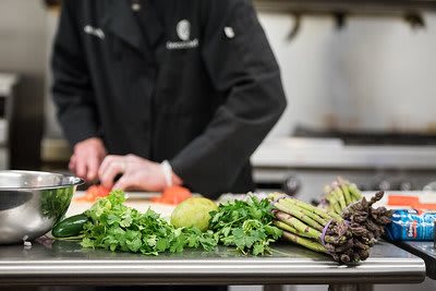 A chef preparing a meal with fresh vegetables in the kitchen.