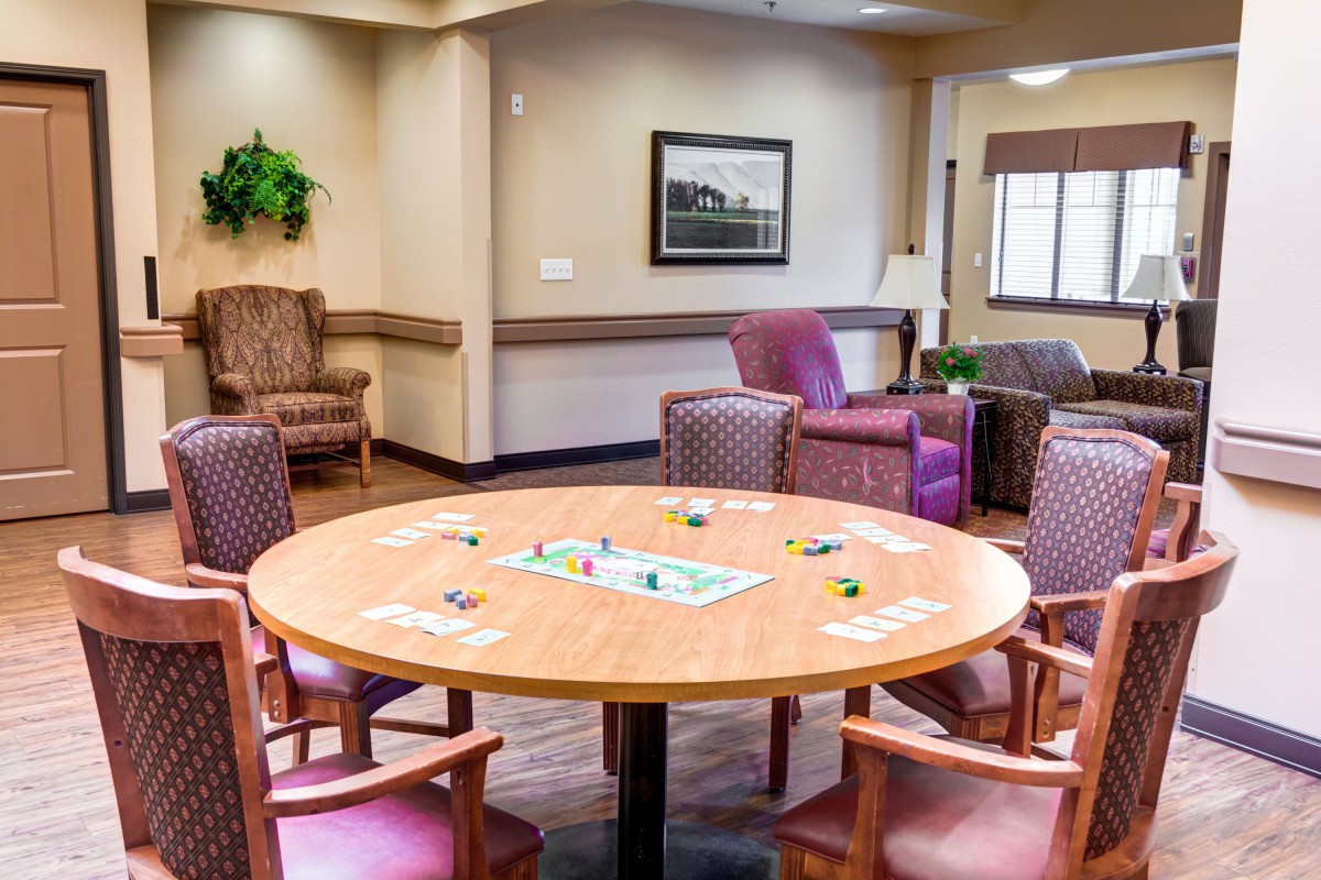 A cozy seating area with a round table set for a board game, surrounded by comfortable chairs.