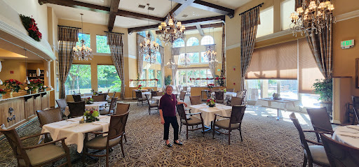 A spacious and elegantly designed dining area featuring large windows, stylish chandeliers, and comfortable seating.
