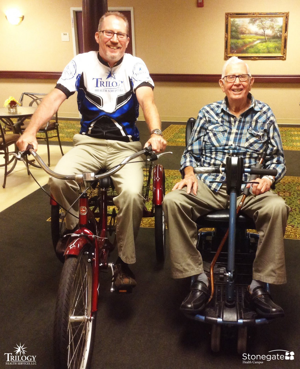 Two elderly men are enjoying a moment indoors, one on a bicycle and the other on a mobility scooter.