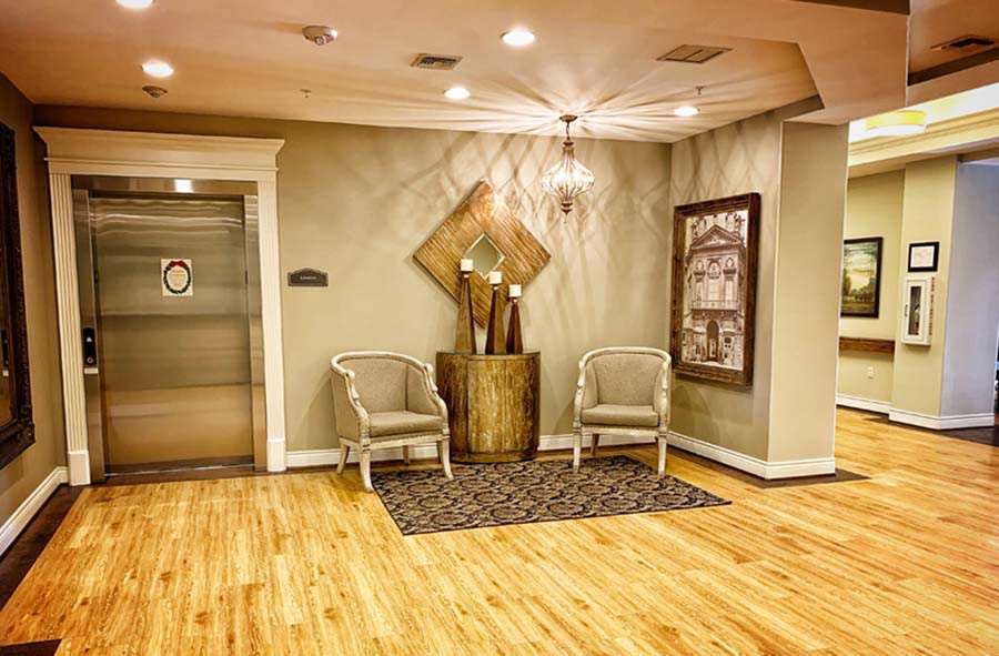 A stylish lobby area featuring elegant decor with chairs, artwork, and a nearby elevator.