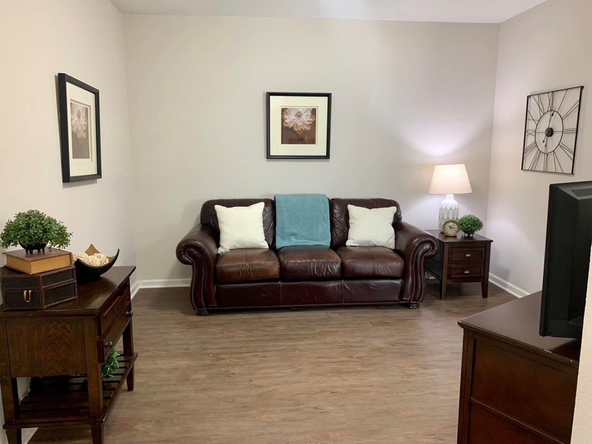 A cozy living room with a leather sofa, side tables, and framed artwork on the walls.