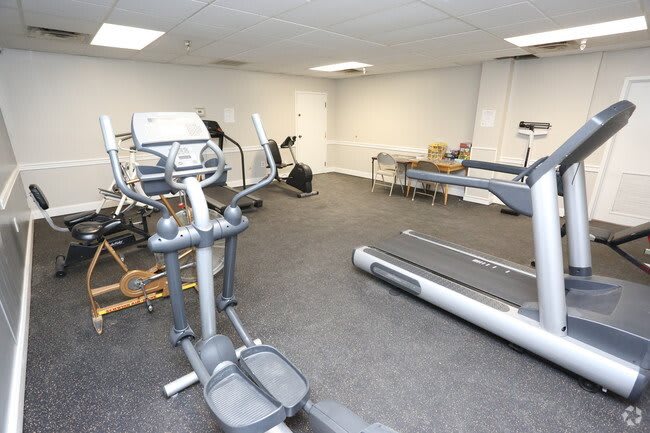 A small indoor gym with various exercise equipment, including treadmills and an elliptical machine.
