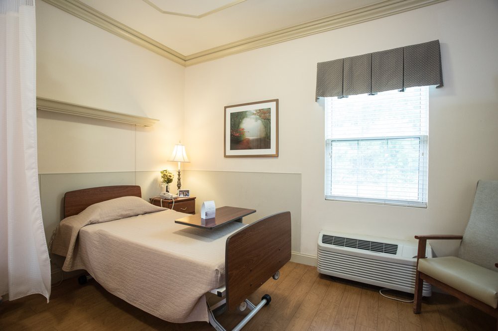A neatly arranged hospital room with a single bed and a window.
