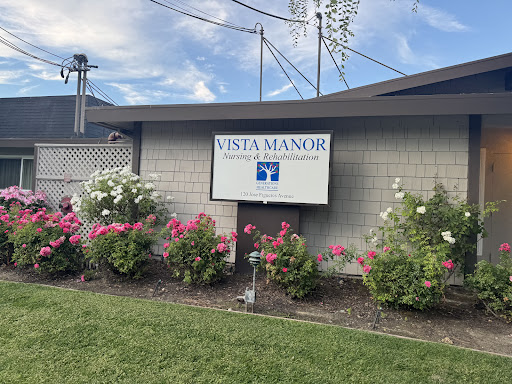 Vista Manor sign surrounded by blooming flowers.
