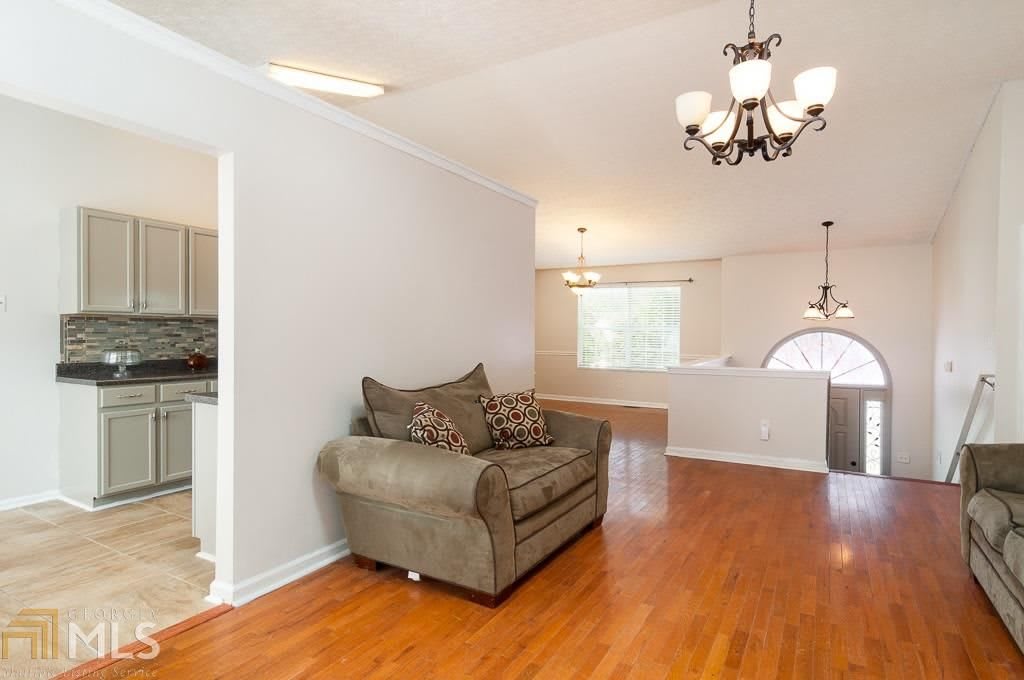 A cozy living room with a single sofa, hardwood flooring, and a chandelier.