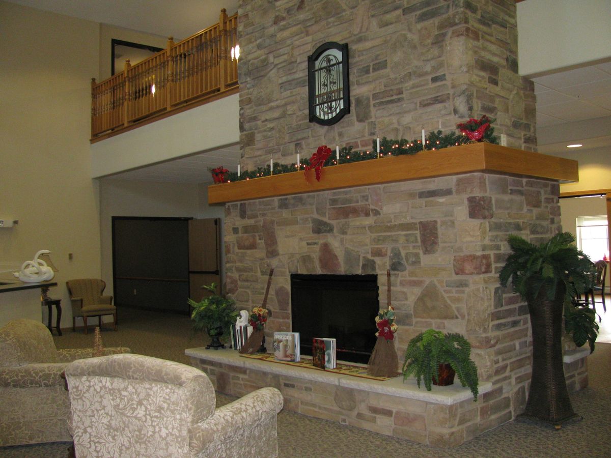 A cozy indoor living area featuring a stone fireplace with decorative items on the mantle and comfortable seating.