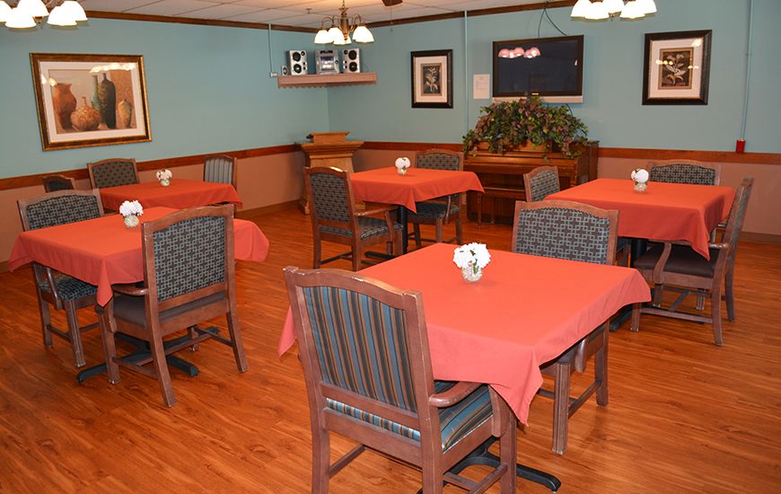A cozy dining room with neatly arranged tables covered in red tablecloths.