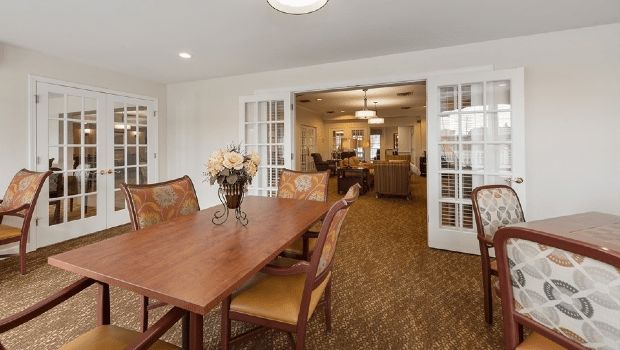 A cozy dining area with a wooden table and chairs, leading into a well-lit living space.