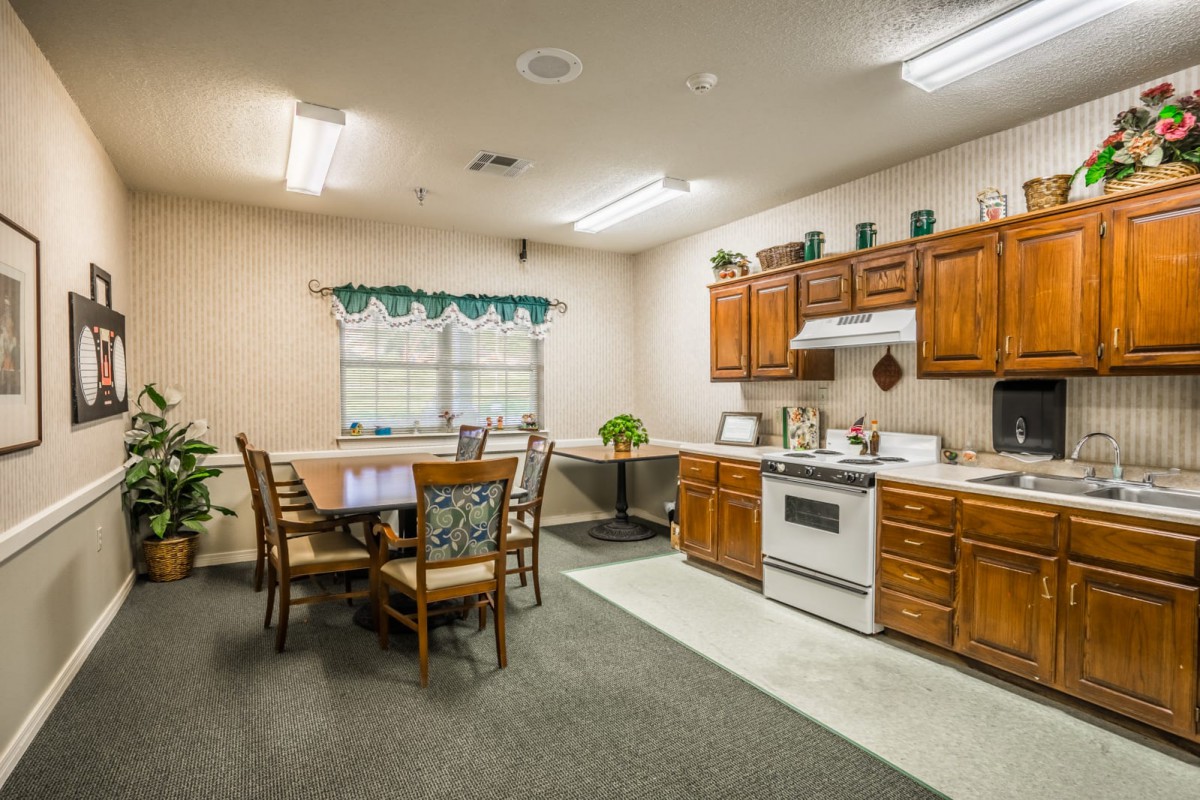 A cozy kitchen and dining area with wooden cabinets, a stove, and a table with chairs.