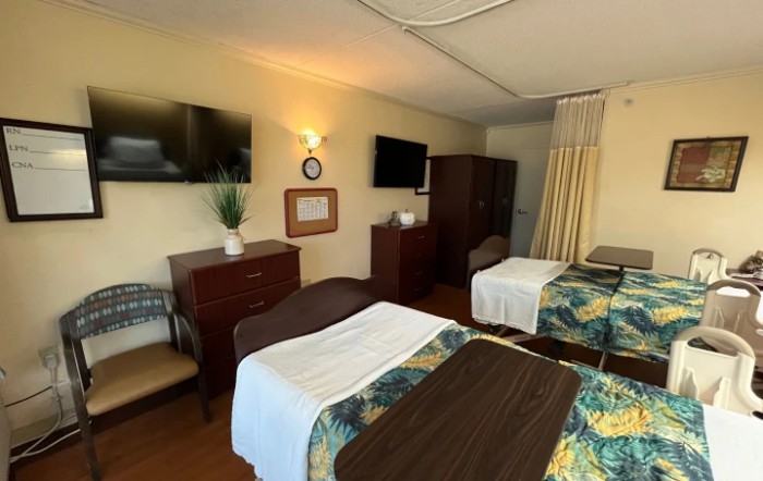 A shared hospital room with two beds, TVs, and a curtain divider.