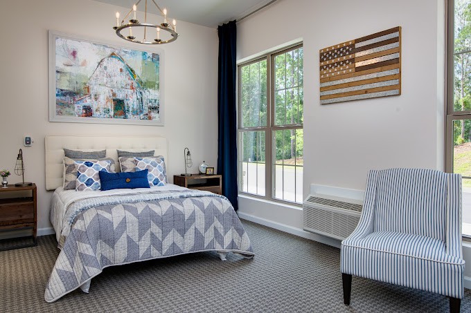 A modern bedroom with stylish decor, featuring a bed with geometric bedding, a large window, and elegant lighting.