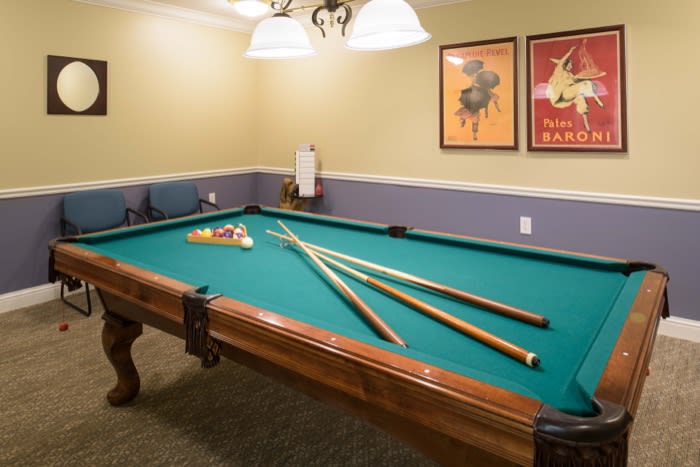 A cozy game room featuring a pool table with cue sticks neatly arranged on its surface.
