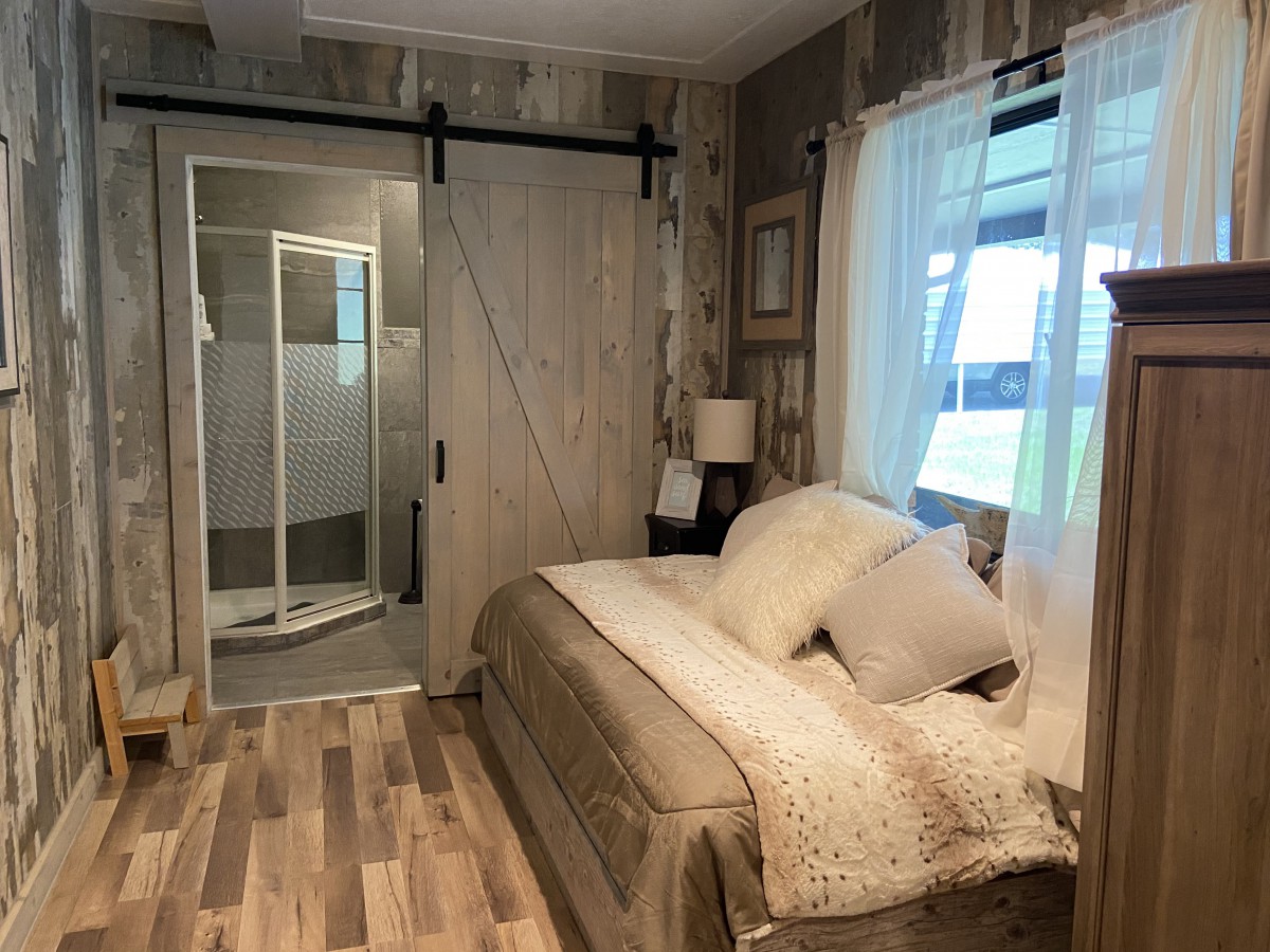 A cozy modern bedroom featuring a sliding barn door and wood flooring.