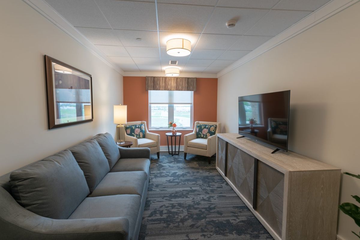 A modern living room featuring a comfortable sofa, television, and seating area with two chairs by the window.