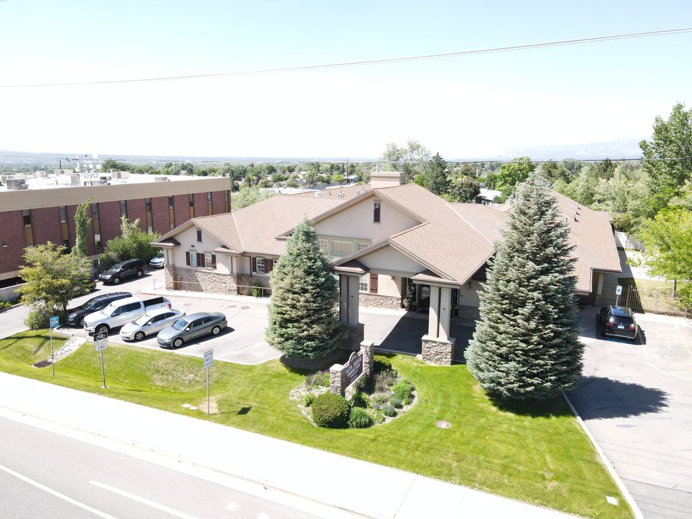 Aerial view of a building with a parking lot and surrounding greenery.