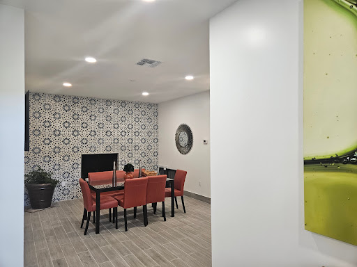 A stylish dining area featuring a modern table and orange chairs against a decorative tiled wall.
