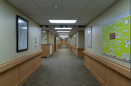A well-lit hallway featuring wooden paneling and various posters on the walls.