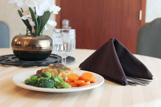 A beautifully arranged plate of vegetables and protein, elegantly served with a glass of water.
