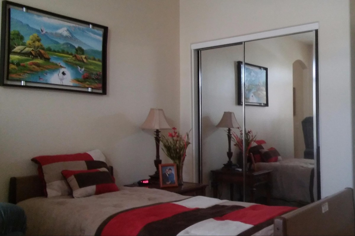 Cozy bedroom with mirrored closet doors, a colorful bedspread, and decorative elements like a lamp and painting.
