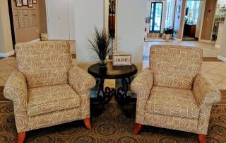 A cozy seating arrangement with two armchairs flanking a small round table in a warmly decorated room.