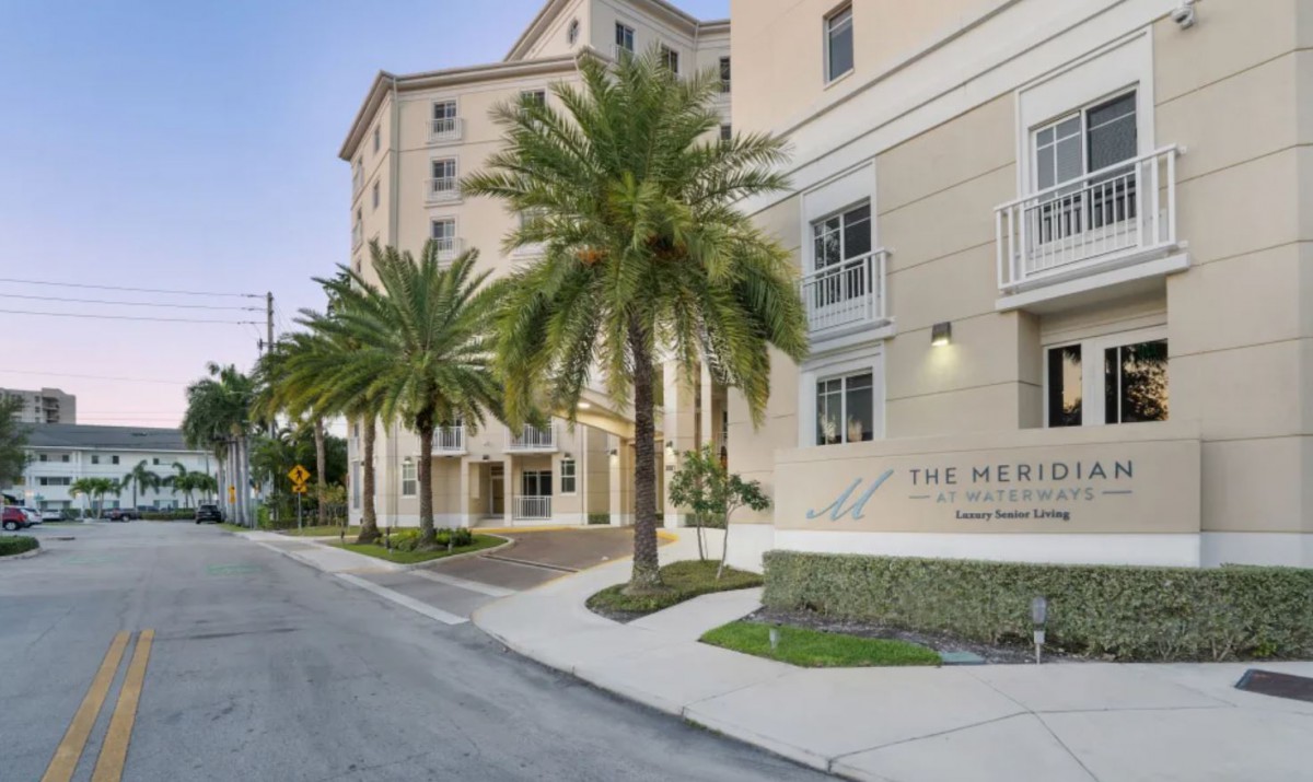 A view of a residential building with palm trees lining the street.