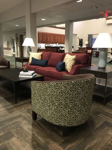 A cozy living room setup featuring a red sofa, patterned armchair, and stylish lamps.