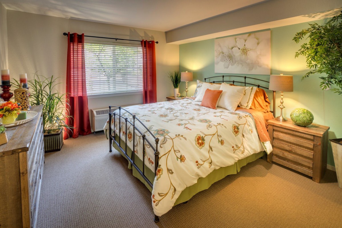 A cozy bedroom with a neatly made bed, soft lighting, and colorful decor.