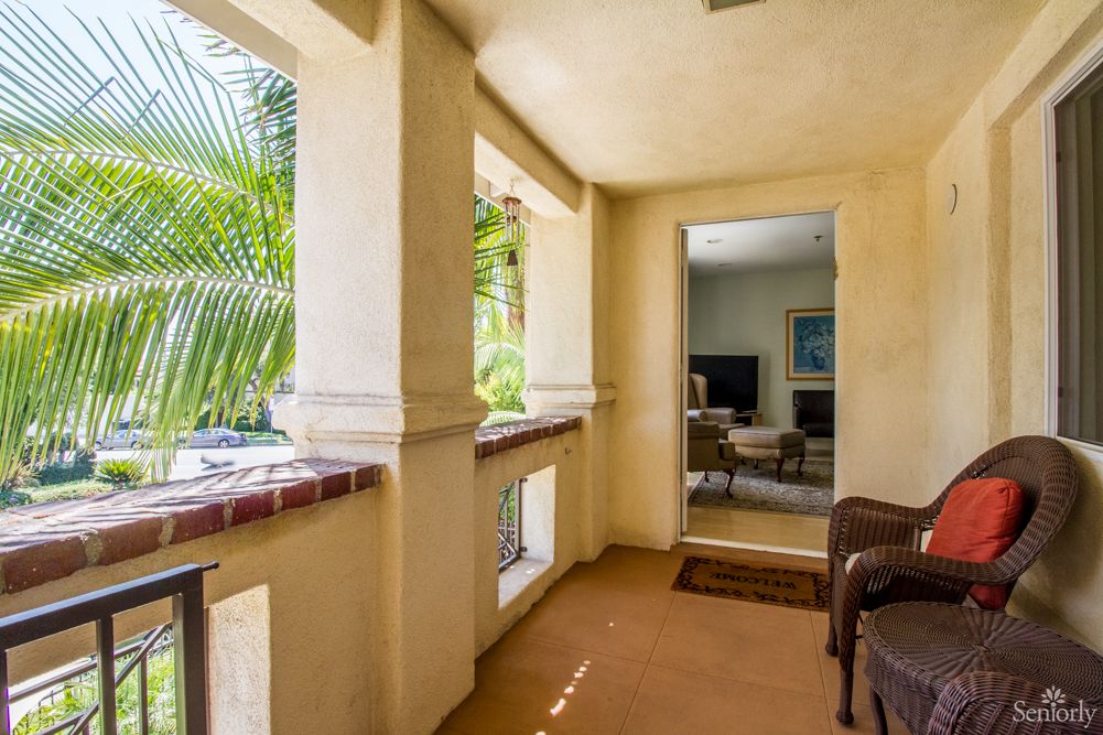A cozy patio area with tropical plants and comfortable seating leading into a living room.