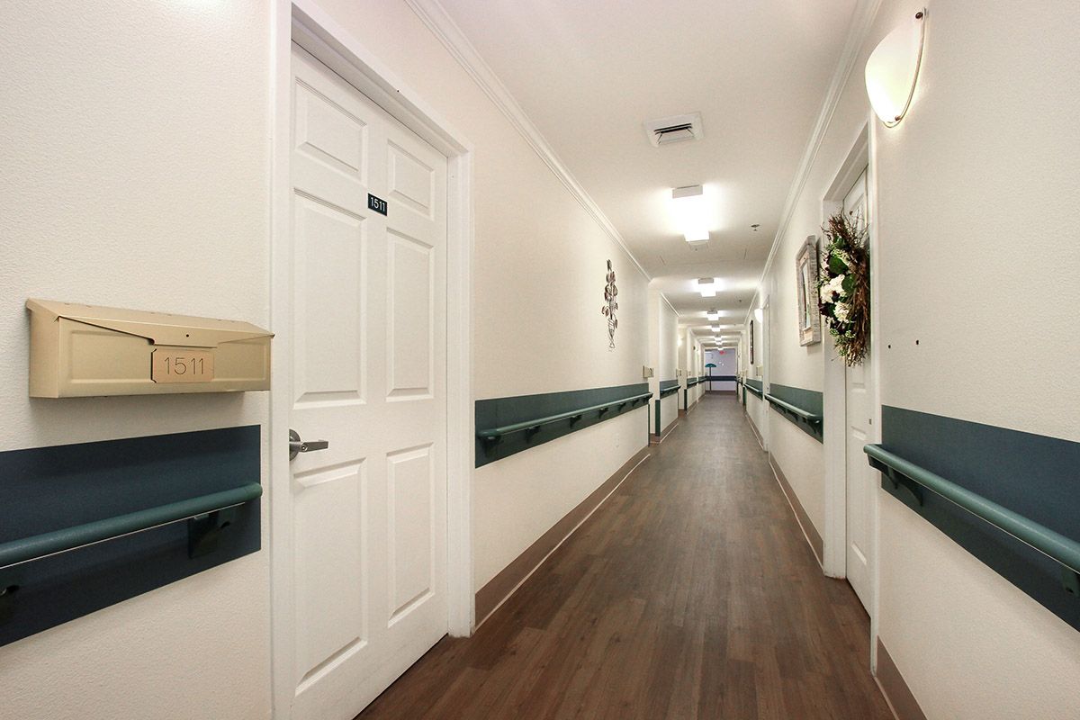 A long, well-lit hallway with wooden flooring and decorated walls.