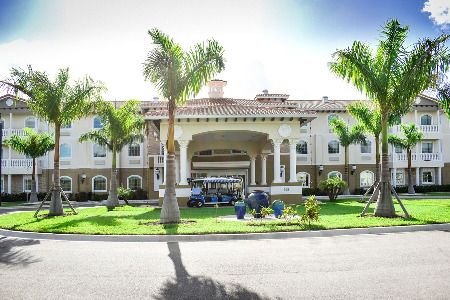 A luxurious resort entrance flanked by palm trees and elegant architecture.